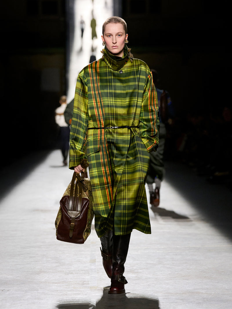 Model wearing a green plaid coat on a runway