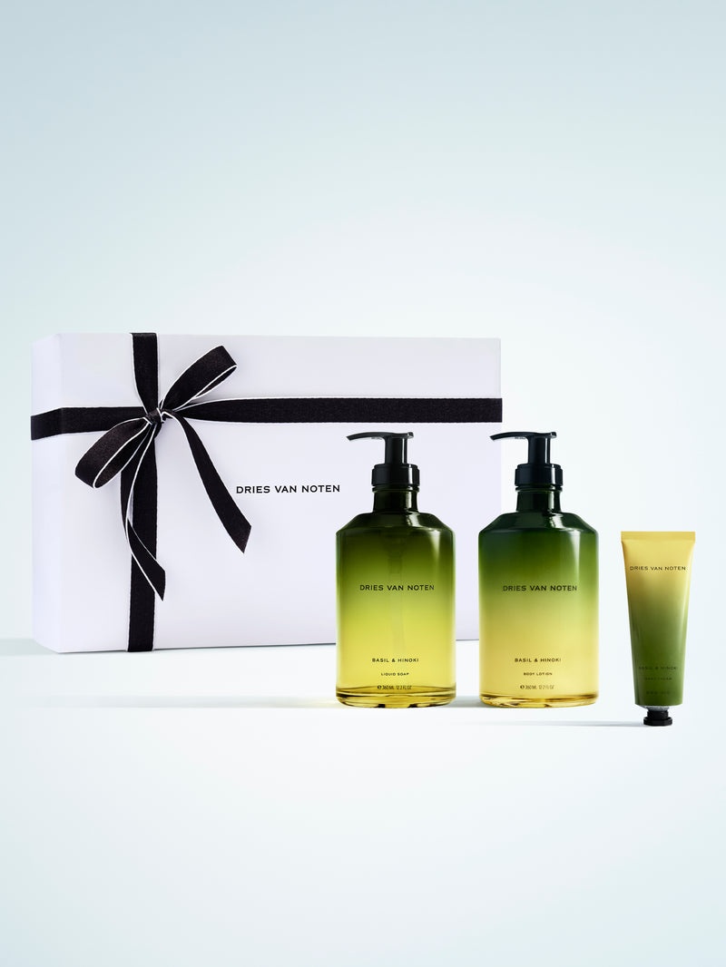 Dries Van Noten gift set featuring two gradient glass liquid soap and body lotion bottles and a matching hand cream, presented beside a white box with a black ribbon on a white background