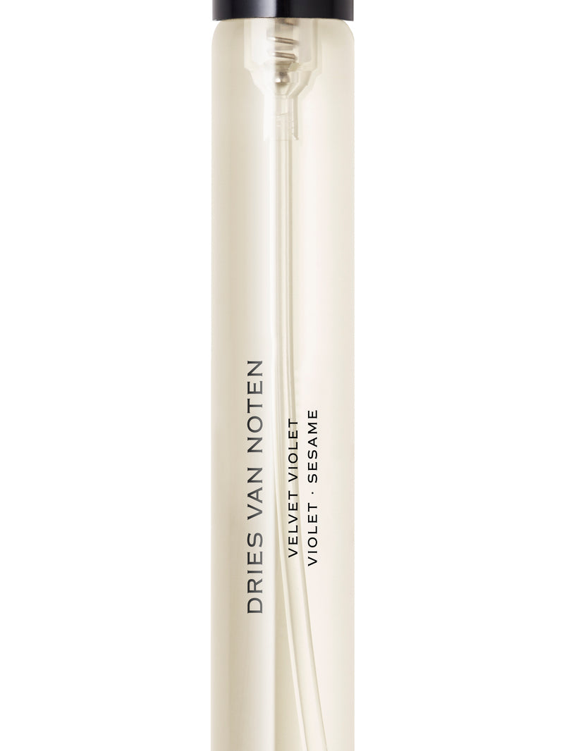 A cylindrical travel spray bottle by Dries Van Noten, featuring a translucent off-white body with a black pump dispenser, shown against a plain white background.