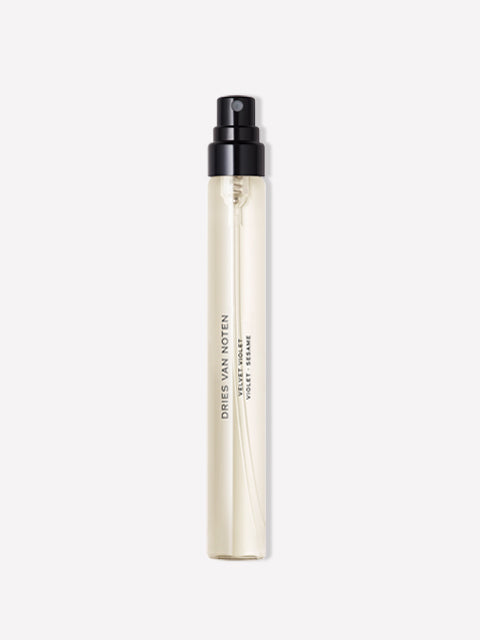 A cylindrical travel spray bottle by Dries Van Noten, featuring a translucent off-white body with a black pump dispenser, shown against a plain white background.