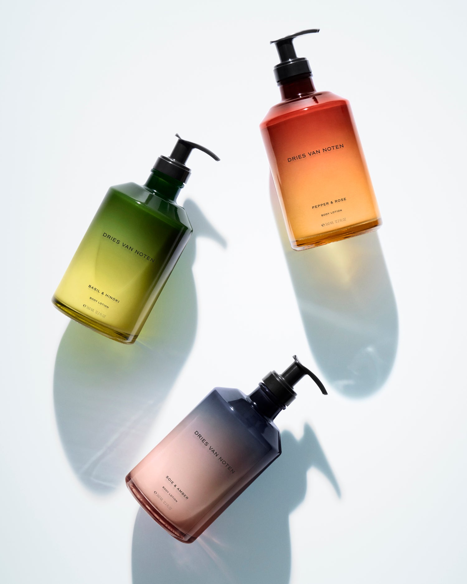 Three Dries Van Noten body lotion bottles in gradient-colored glass 