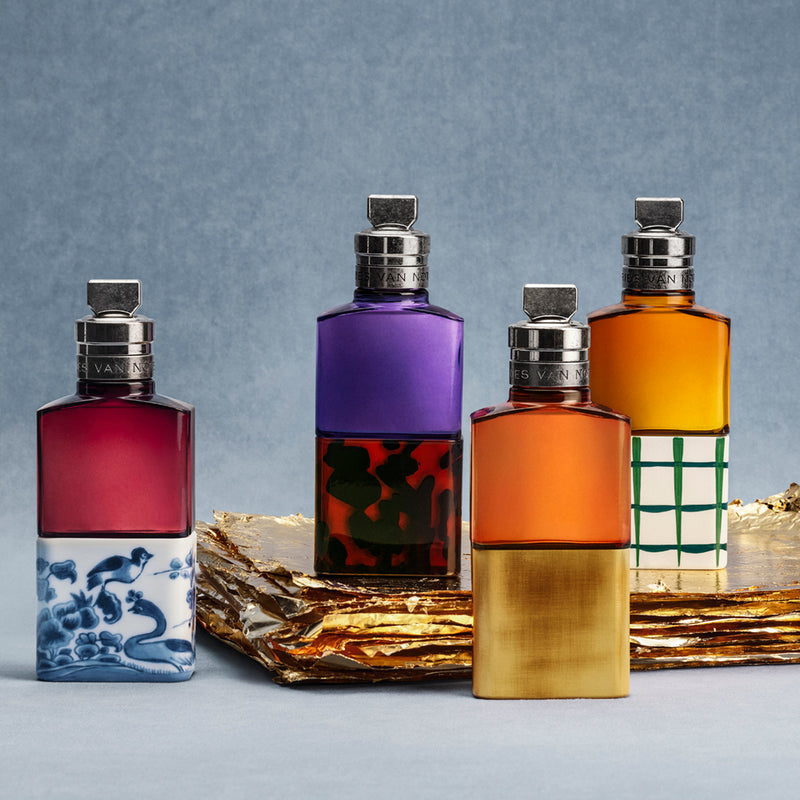 Four colorful perfume bottles with decorative labels on a gray background