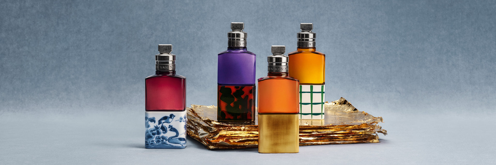 Four colorful perfume bottles on a decorative tray with a gray background