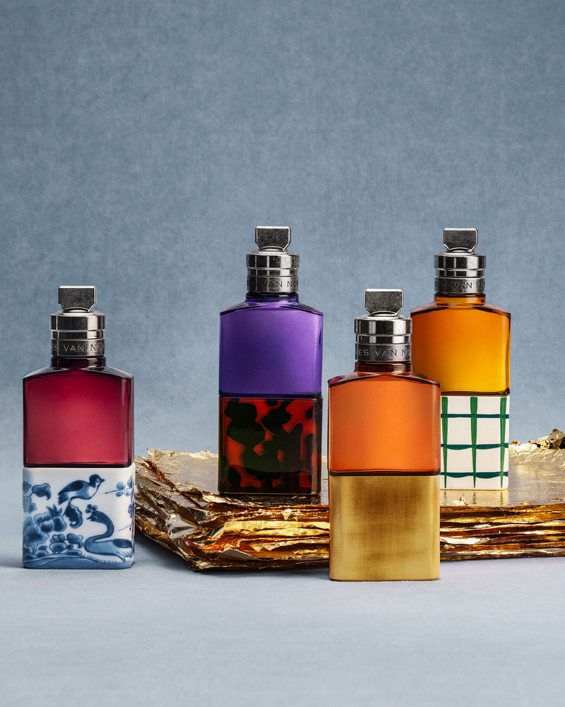 Four colorful perfume bottles with decorative labels on a textured surface.