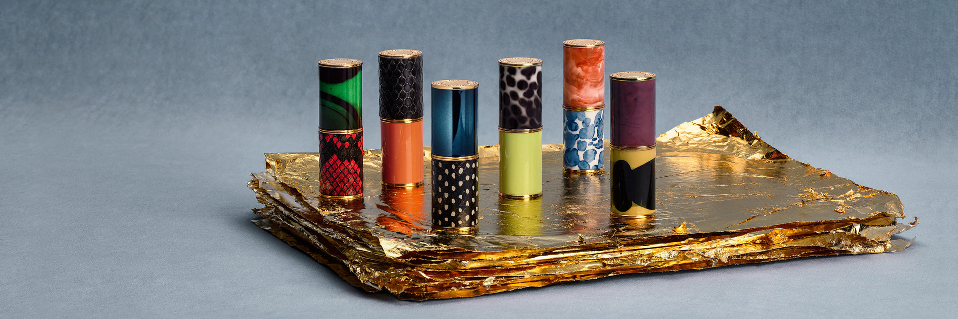 Colorful lipsticks on a decorative tray against a gray background