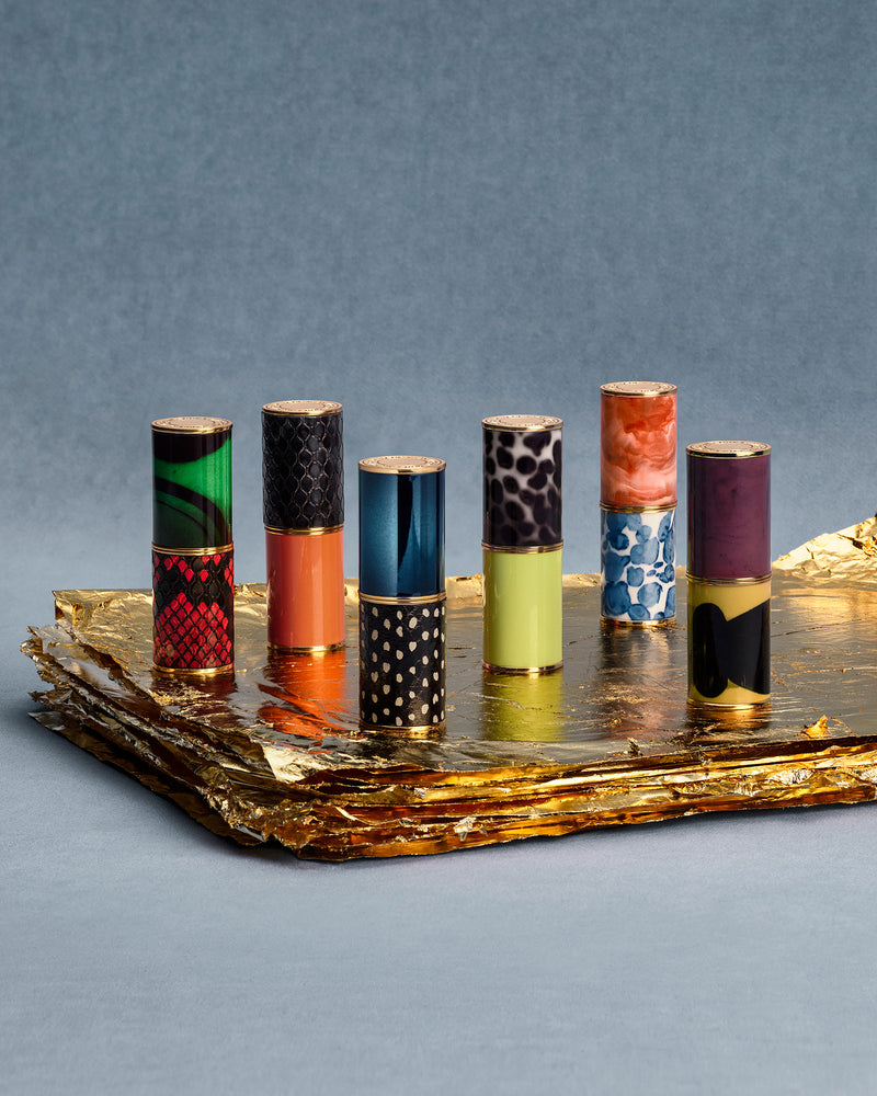 Set of colorful lipsticks on a reflective surface with a gray background