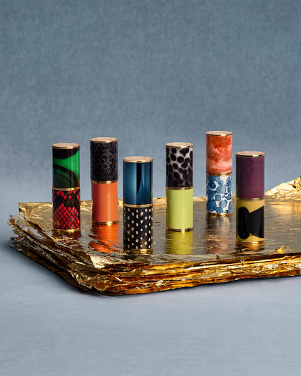 Set of colorful lipsticks on a reflective surface with a gray background