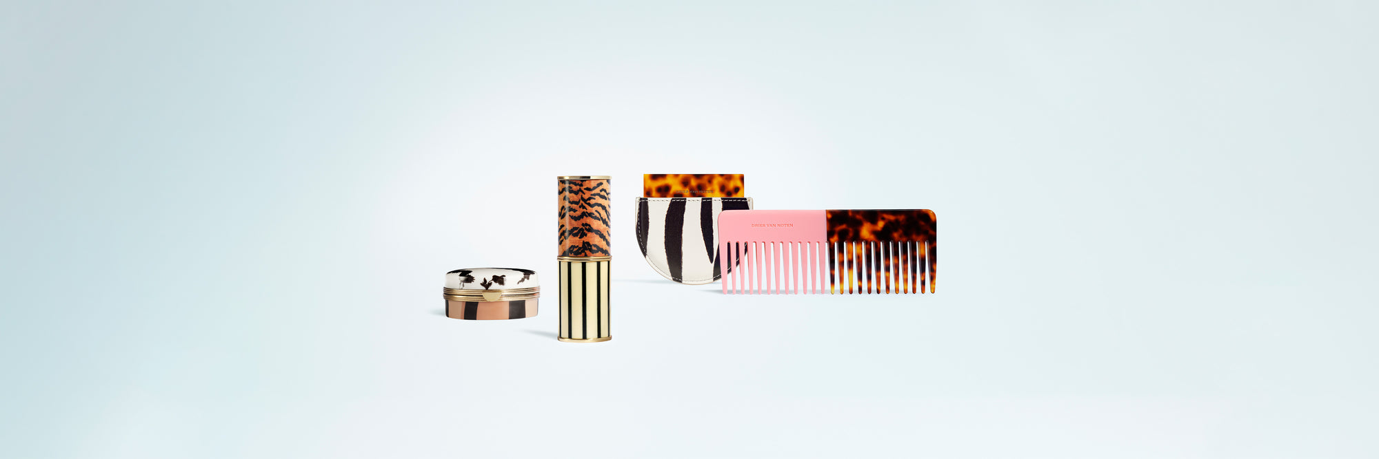 Set of cosmetic products and accessories including a lip box, lipstick case, mirror and a comb on a light blue background