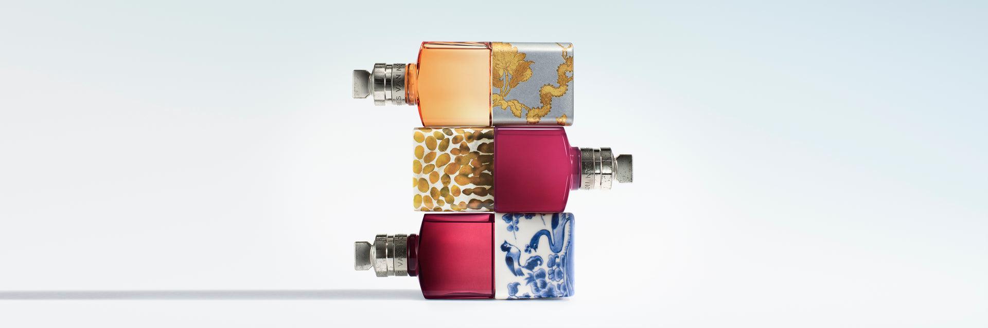 Three rectangular fragrance bottles stacked vertically on a light blue gradient background.
