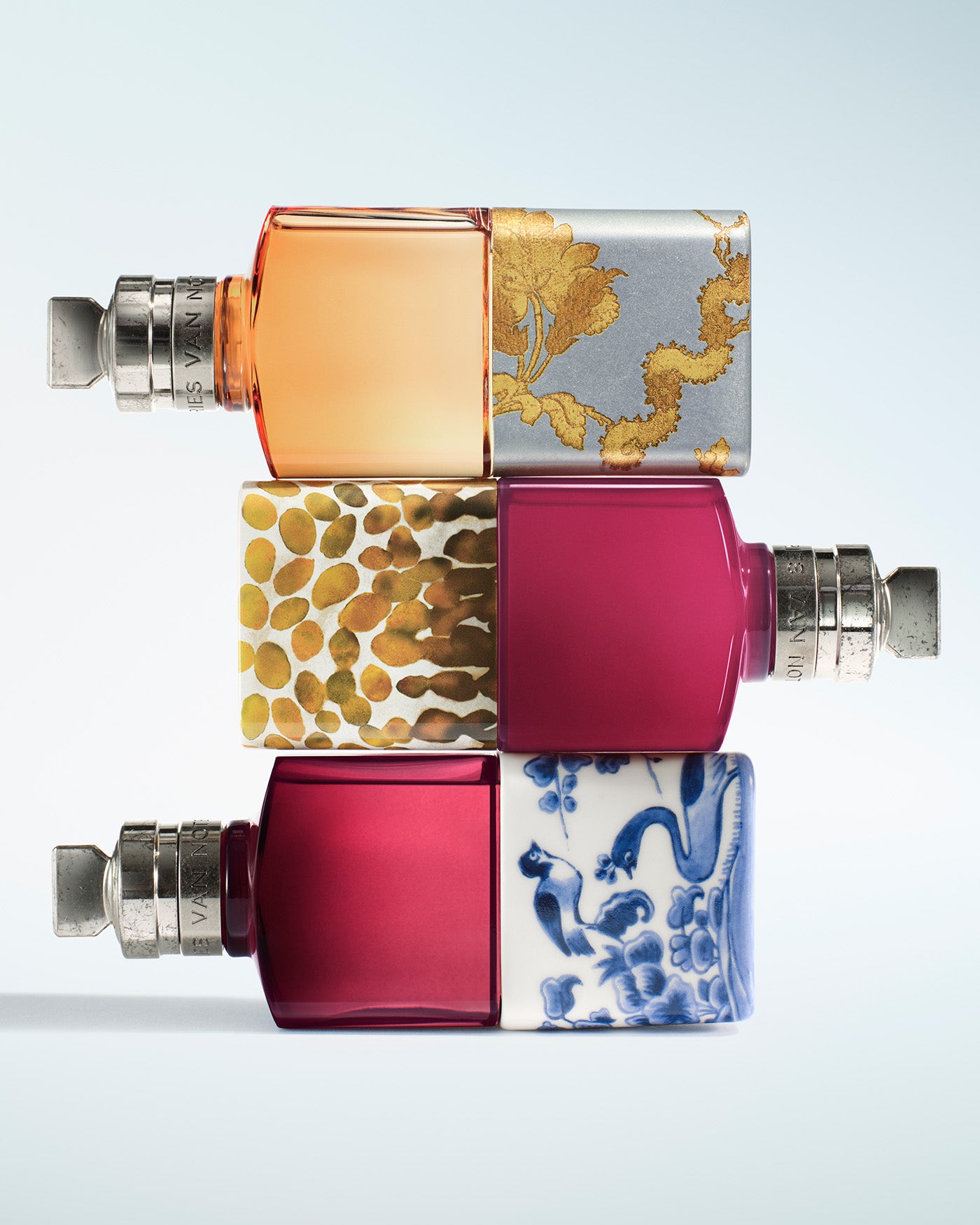 Three rectangular perfume bottles stacked vertically, each with a silver atomizer. 