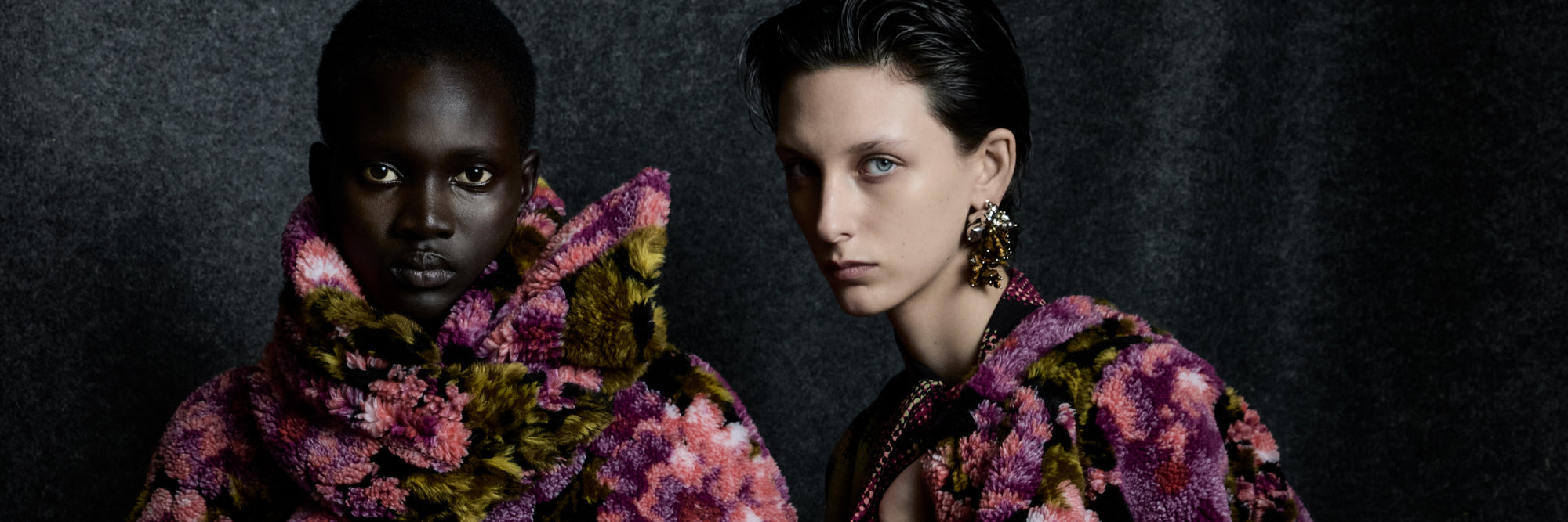 Woman wearing a colorful floral-patterned coat against a dark background