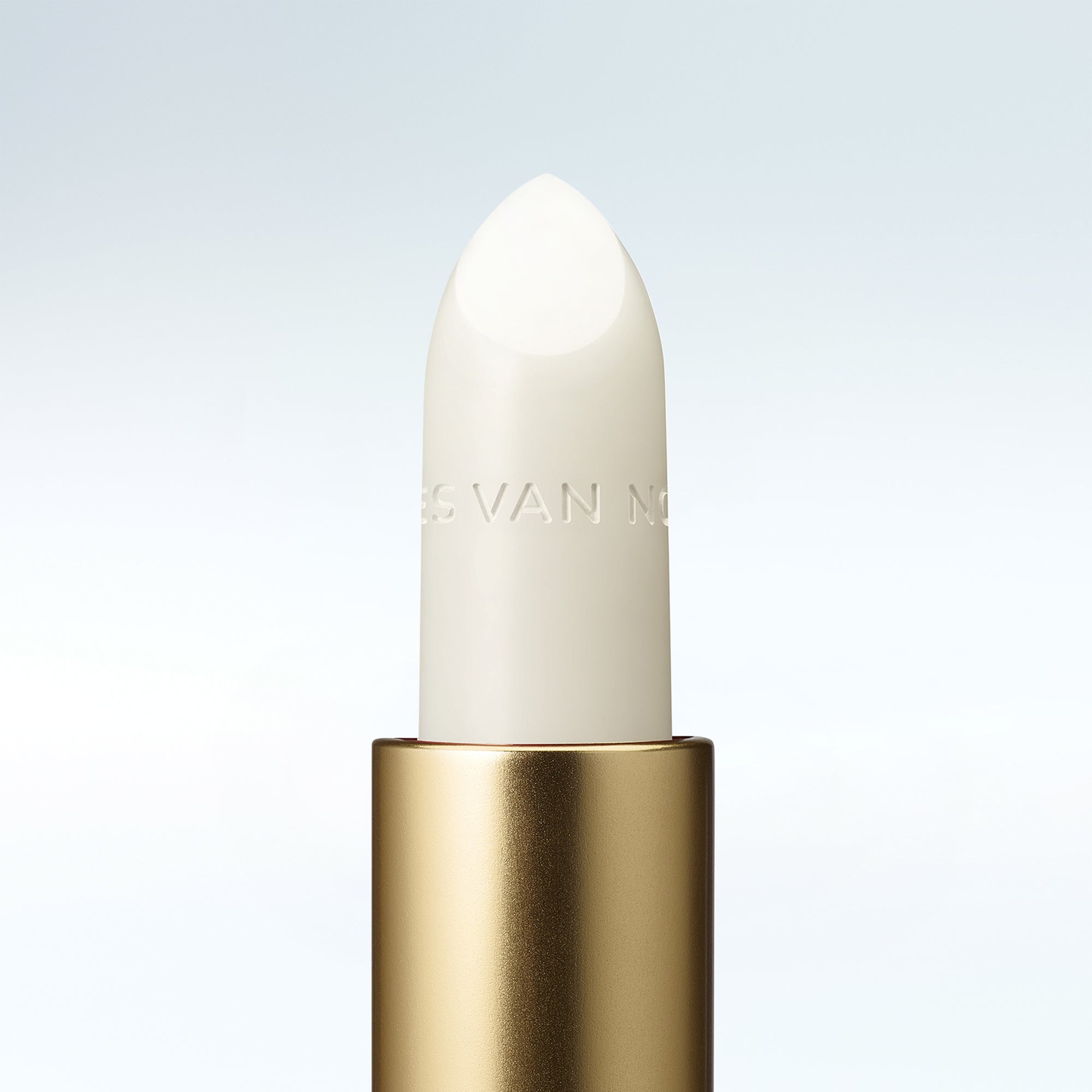 Close-up of a Dries Van Noten balm in a gold tube against a clean white background 