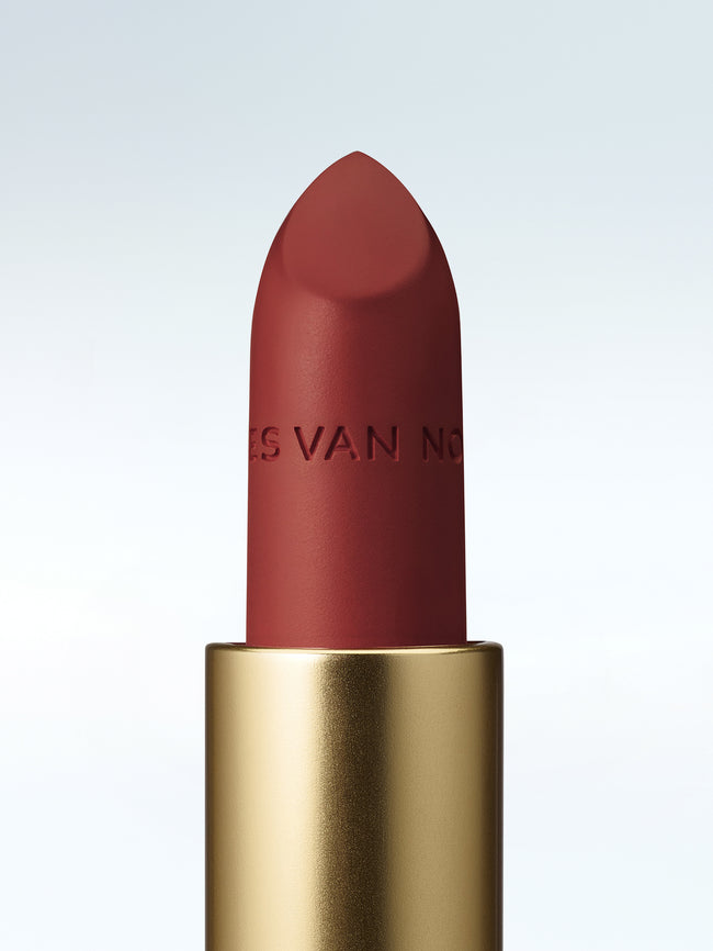 Close-up of a Dries Van Noten lipstick in a gold tube against a cold white background 