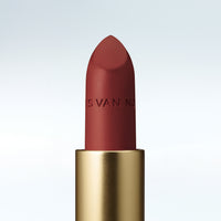 Close-up of a Dries Van Noten lipstick in a gold tube against a cold white background 