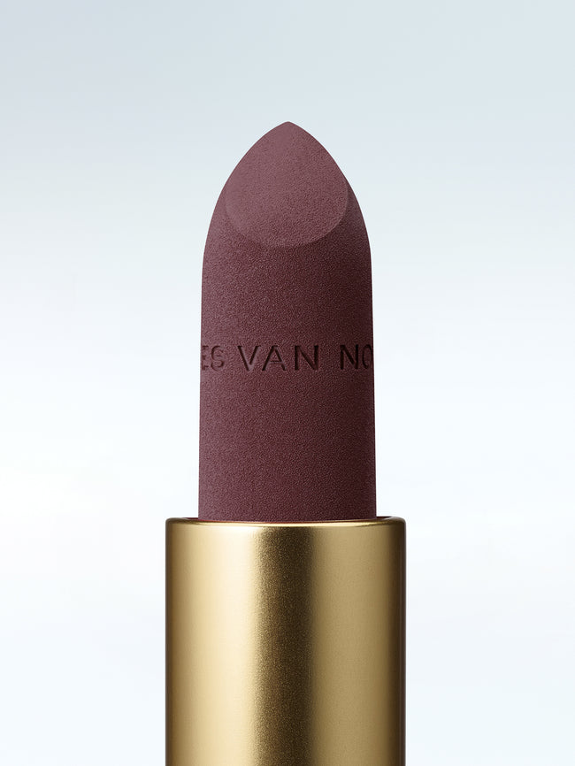 Close-up of a Dries Van Noten lipstick in a gold tube against a cold white background