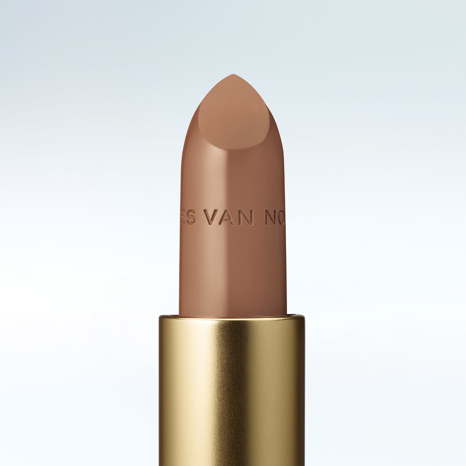 Close-up of a Dries Van Noten lipstick in a gold tube against a cold white background