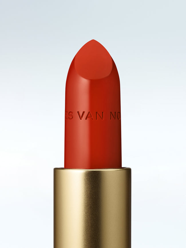 Close-up of a Dries Van Noten lipstick in a gold tube against a cold white background