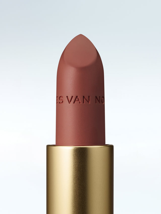 Close-up of a Dries Van Noten lipstick in a gold tube against a cold white background
