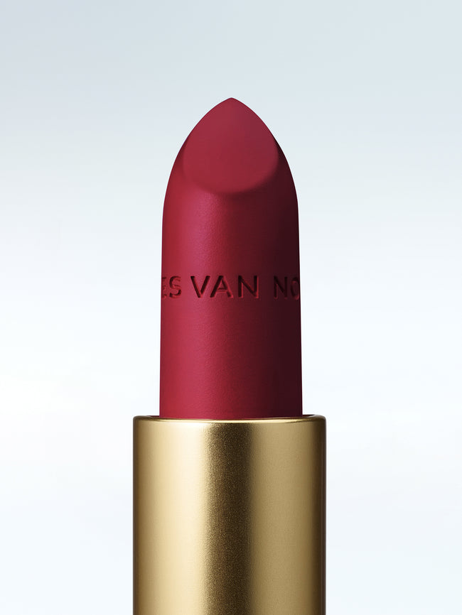 Close-up of a Dries Van Noten lipstick in a gold tube against a cold white background 