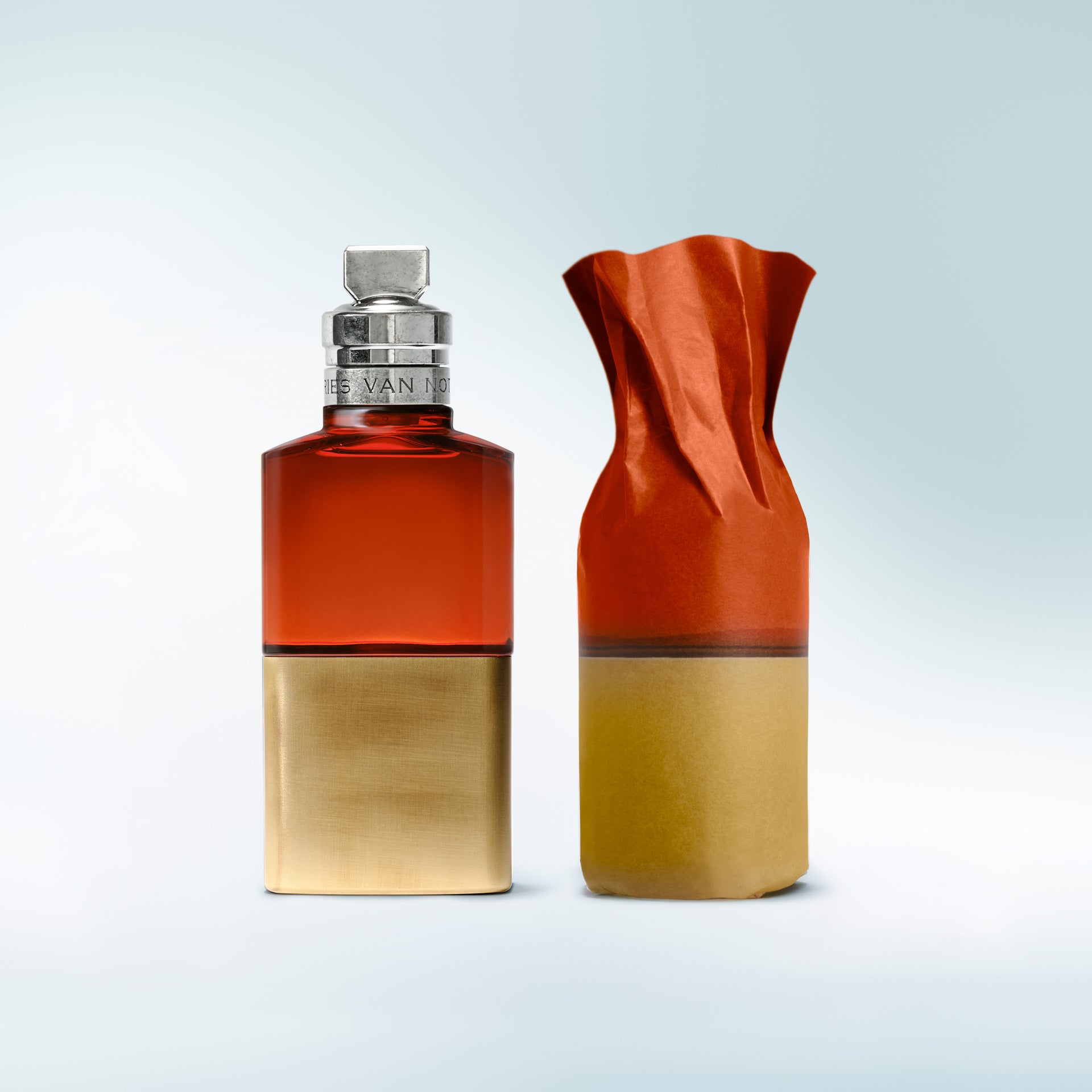 Two bottles, one red and gold, the other orange and gold, on a light gray background.