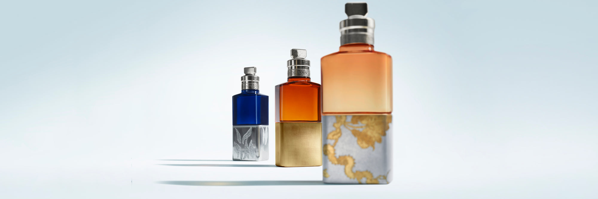 Four perfume bottles of different sizes on a white shelf with a light gray background - Dries Van Noten