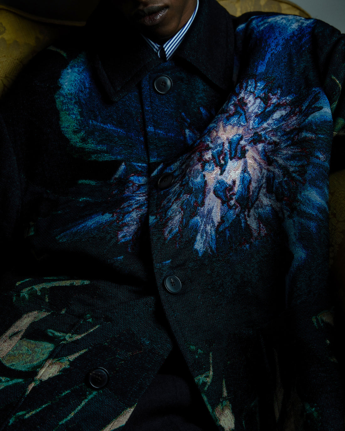 Person wearing a dark coat with floral patterns in blue and green.