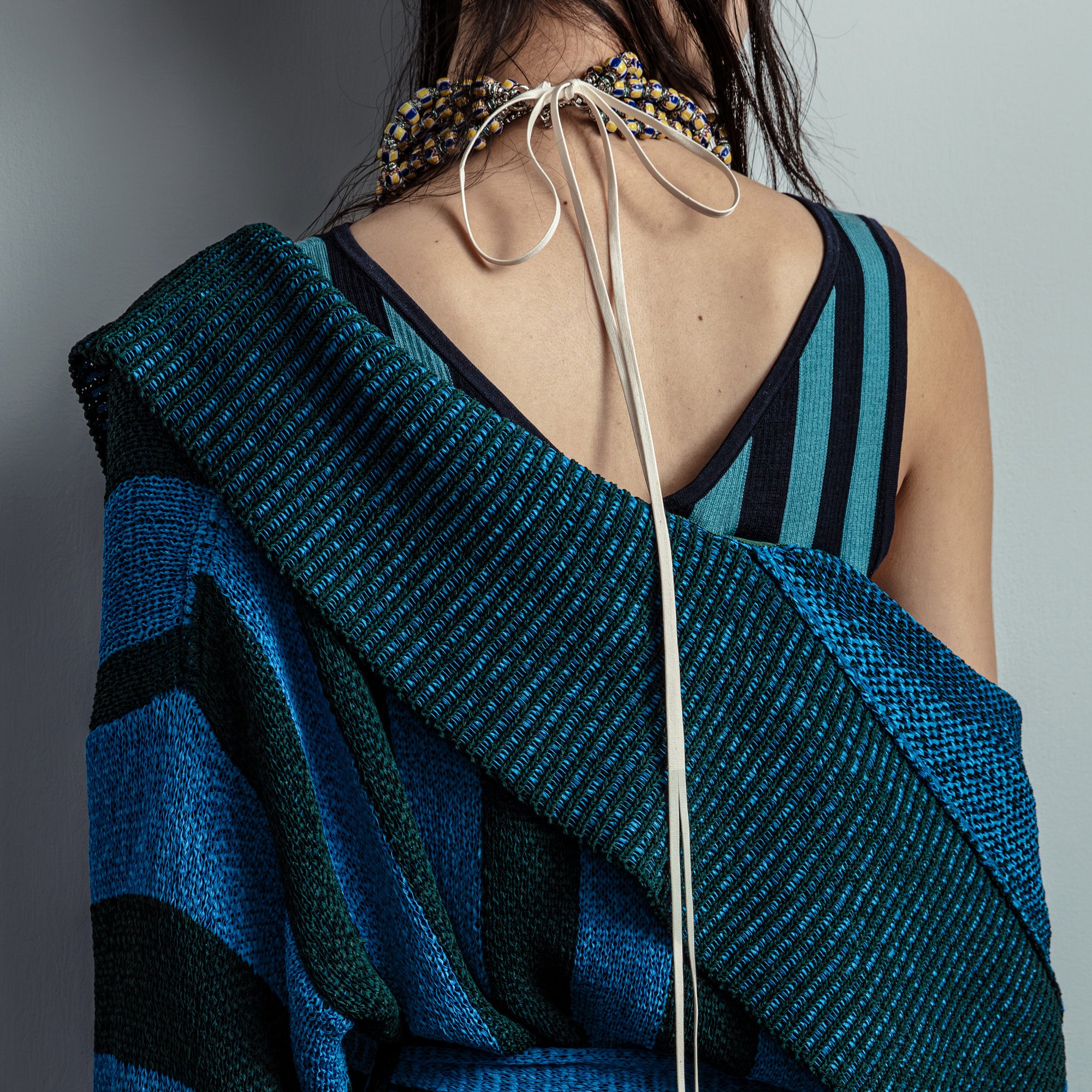 Person wearing a blue and black patterned garment with a gray background- Dries Van Noten