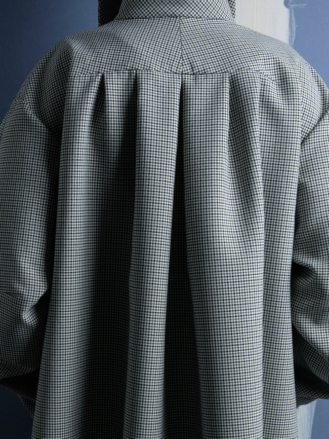 Back view of a person wearing a checkered shirt against a blue background