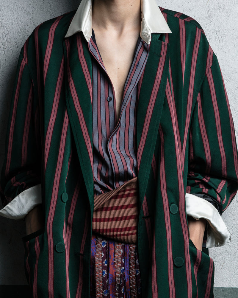 Person standing against a white wall wearing a colorful outfit - Dries Van Noten