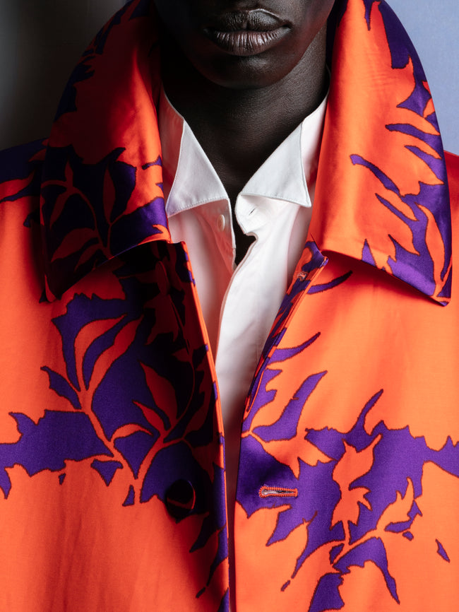 Person wearing an orange and purple patterned shirt with a white collar.