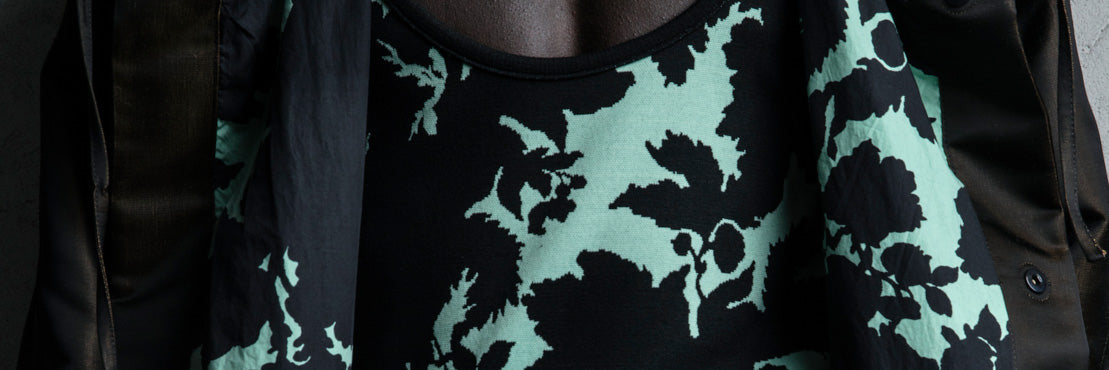 Close-up of a person wearing a dark jacket and turquoise floral patterned garment.