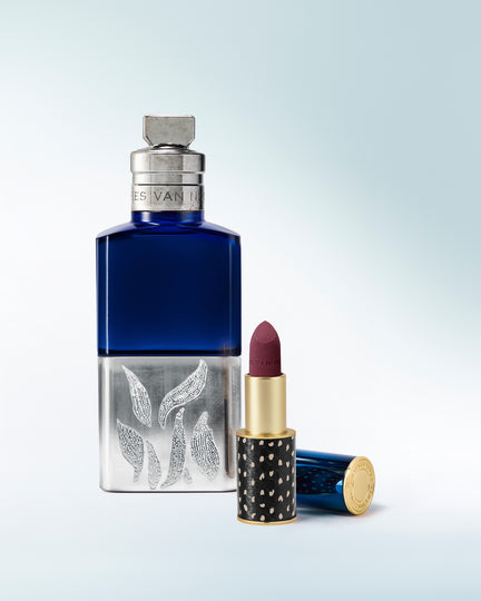 Blue perfume bottle and red lipstick with decorative packaging on a light gray background - Dries Van Noten