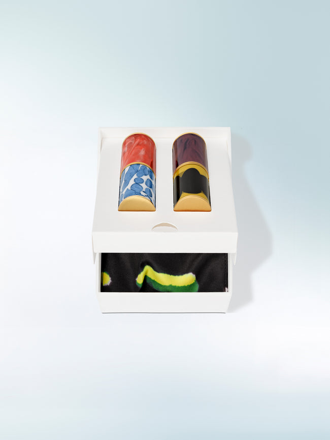 Box of lipsticks with colorful designs on a light blue background