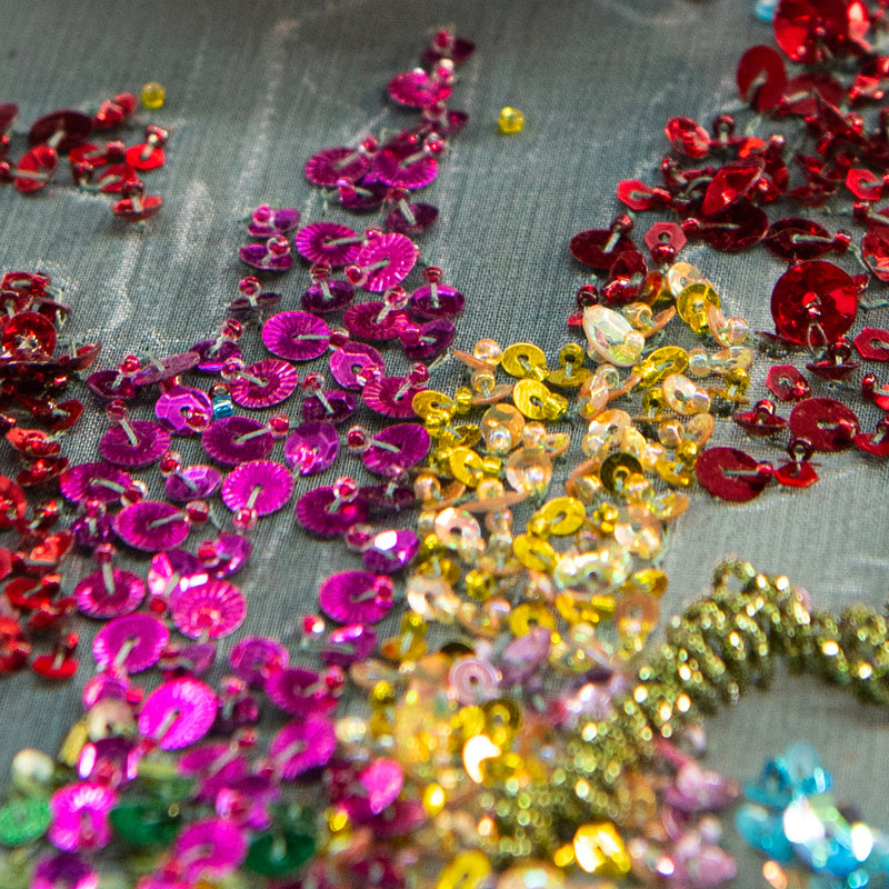 Multicolored sequins on a gray see-through fabric background