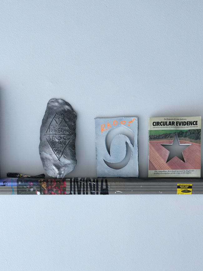 Collection of books and decorative items on a shelf against a white wall