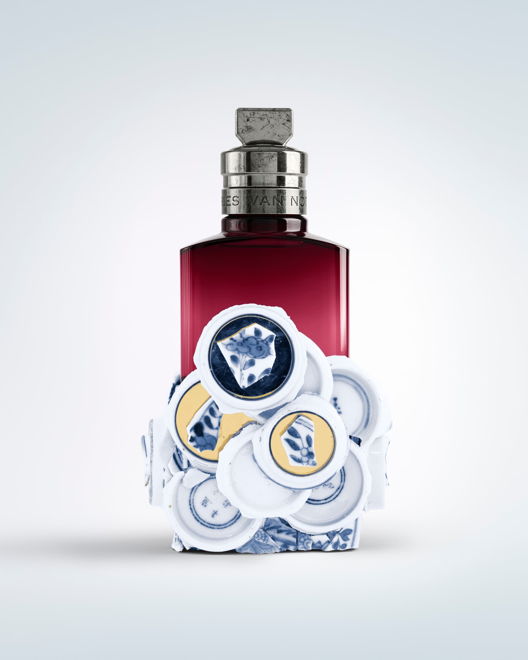 Perfume bottle with decorative cap on a light gray background - Dries Van Noten