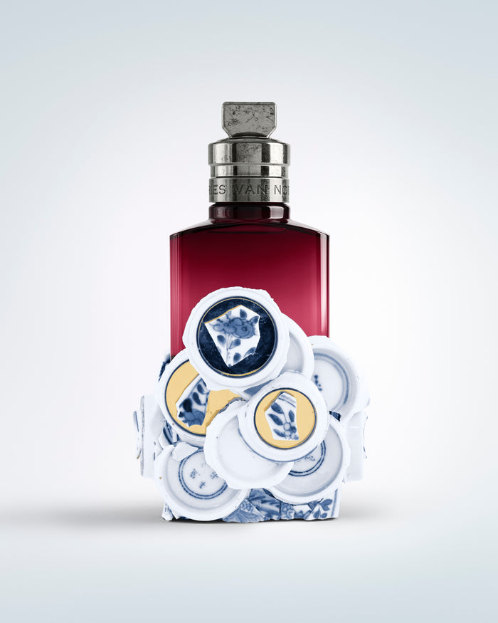 Perfume bottle with decorative cap on a light gray background - Dries Van Noten
