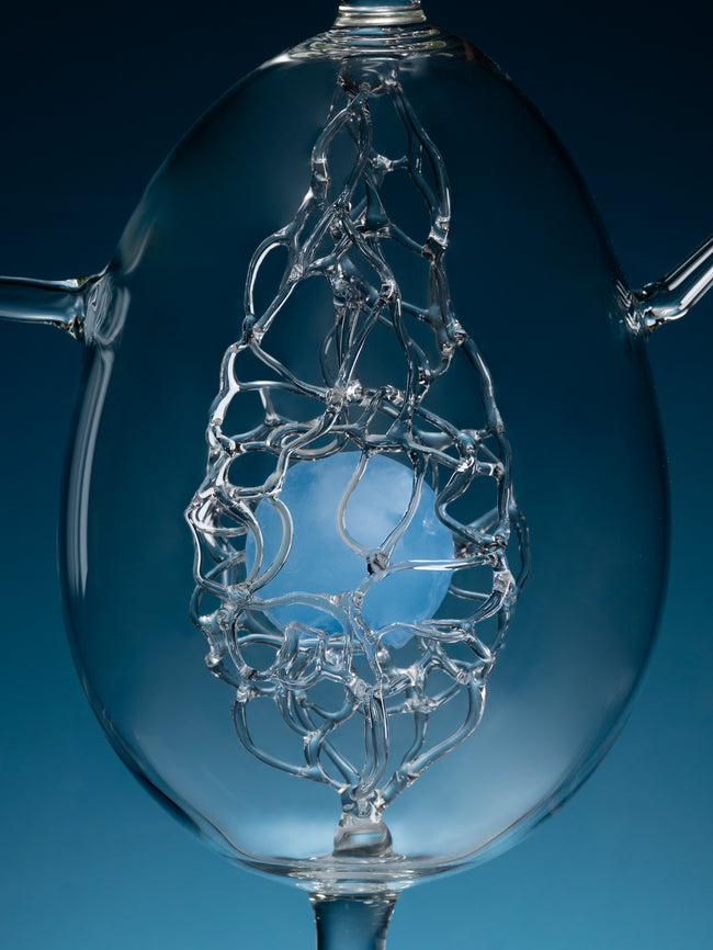 Clear glass object with intricate design against a blue background