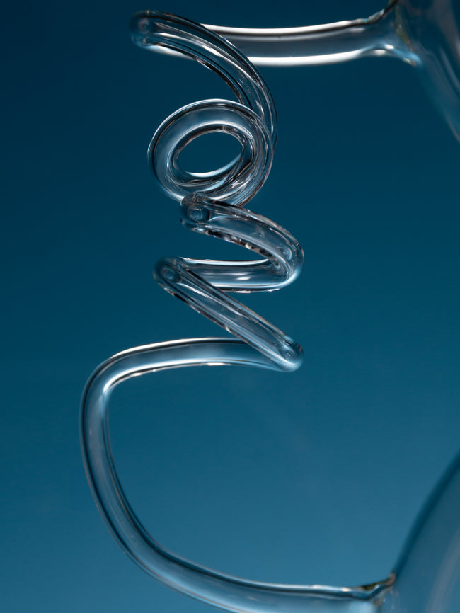 Close-up of a glass water pipe with a coil on a blue background