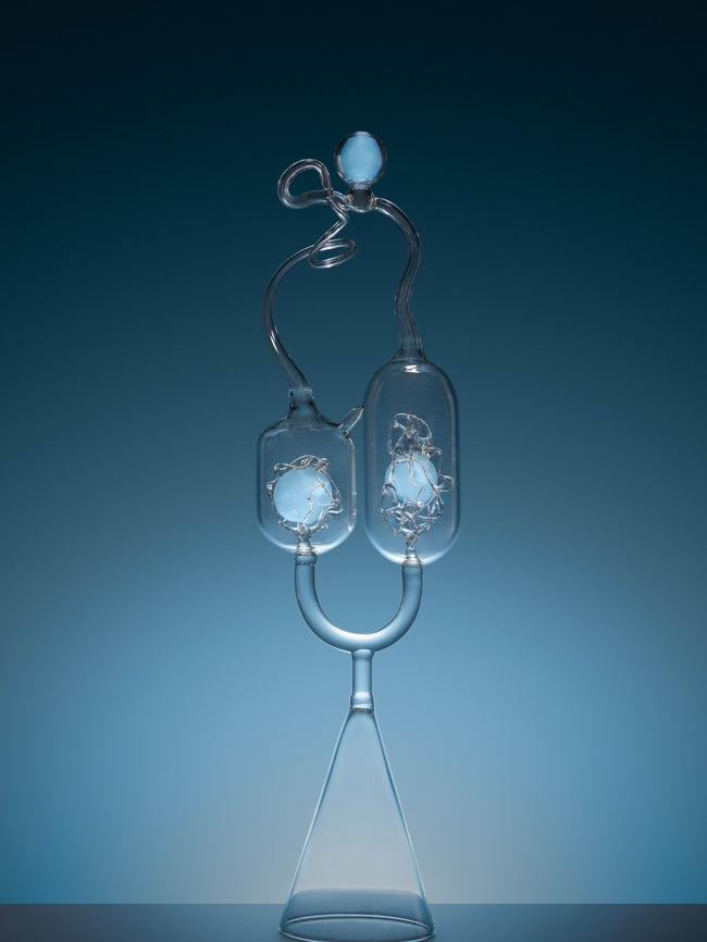 Close-up of a clear glass light bulb against a dark blue background