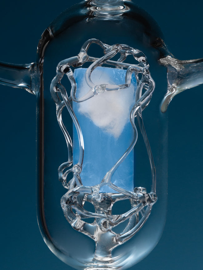 Close-up of a clear glass light bulb against a dark blue background