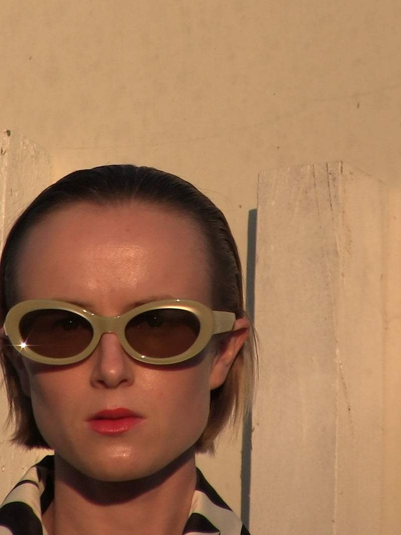 Person wearing oval sunglasses with a neutral background