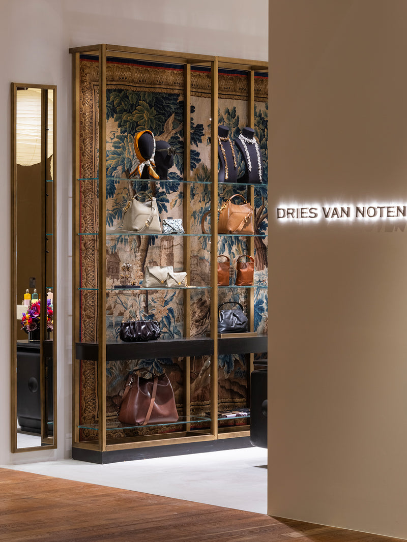 A luxury display cabinet filled with designer handbags, set in a high-end boutique Dries Van Noten.