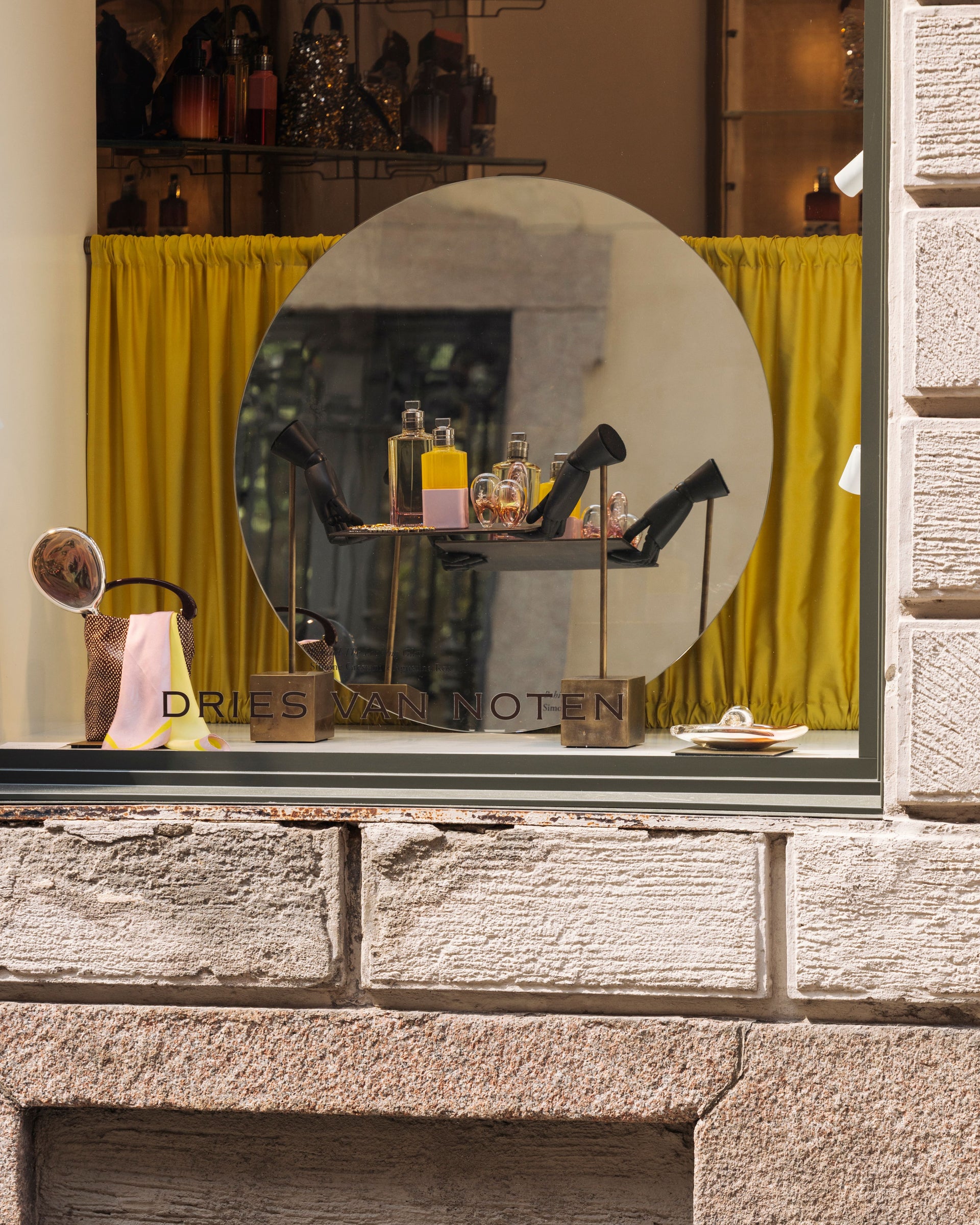 Store window display with 'Dries Van Noten' branding, featuring shoes and accessories.