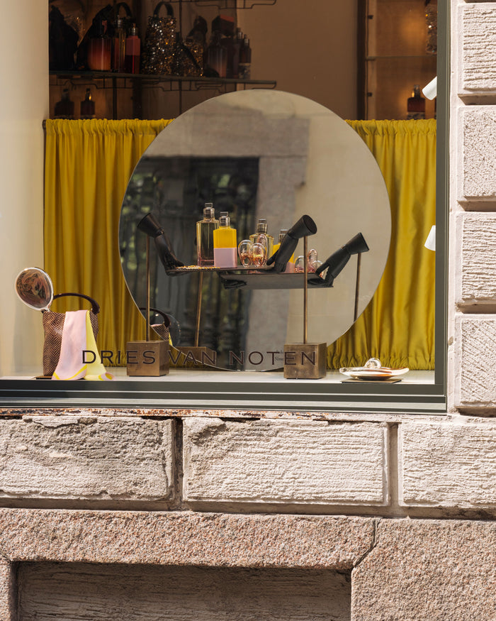 Store window display with 'Dries Van Noten' branding, featuring shoes and accessories.