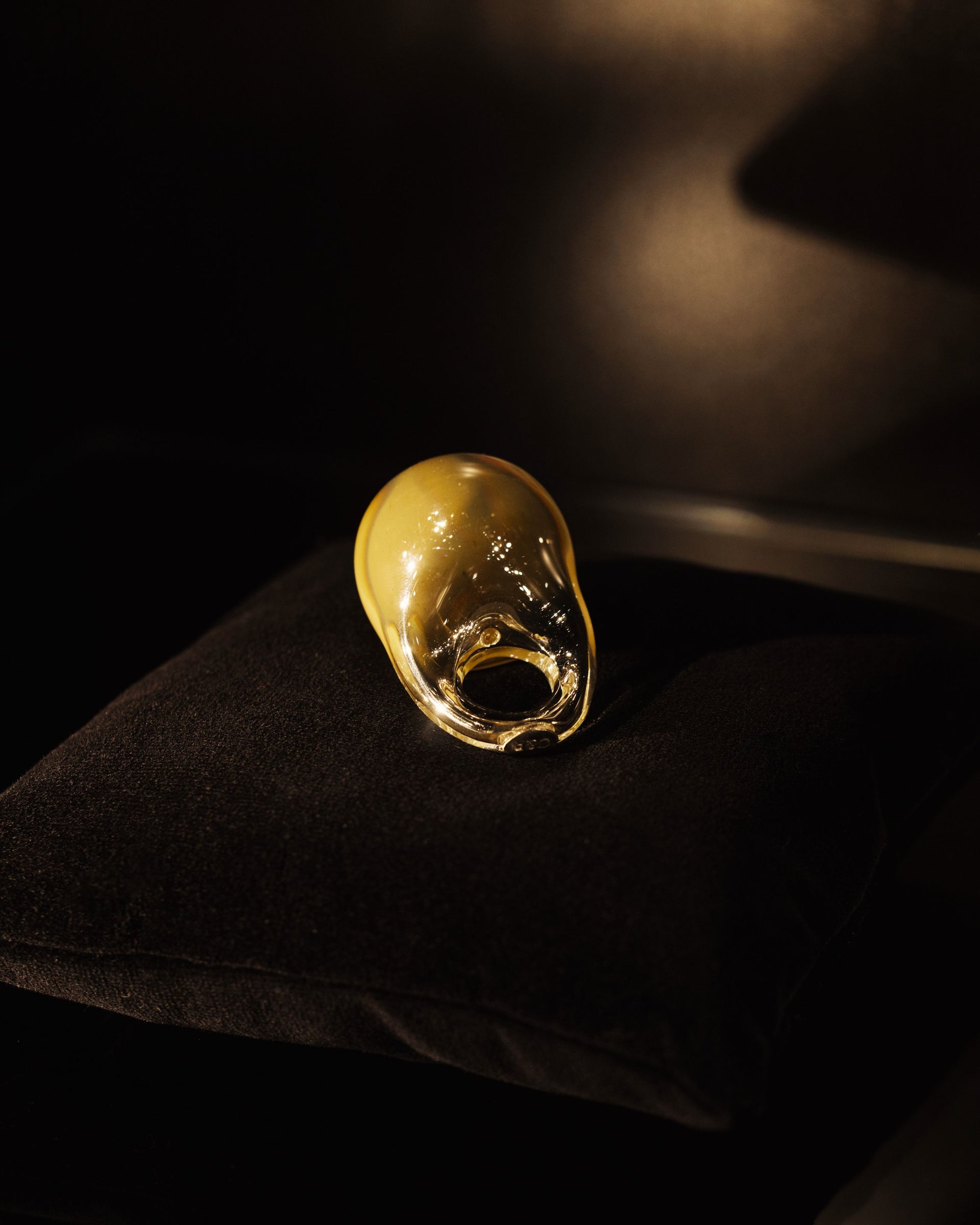 Close-up of molten glass being formed on a rod against a dark background 