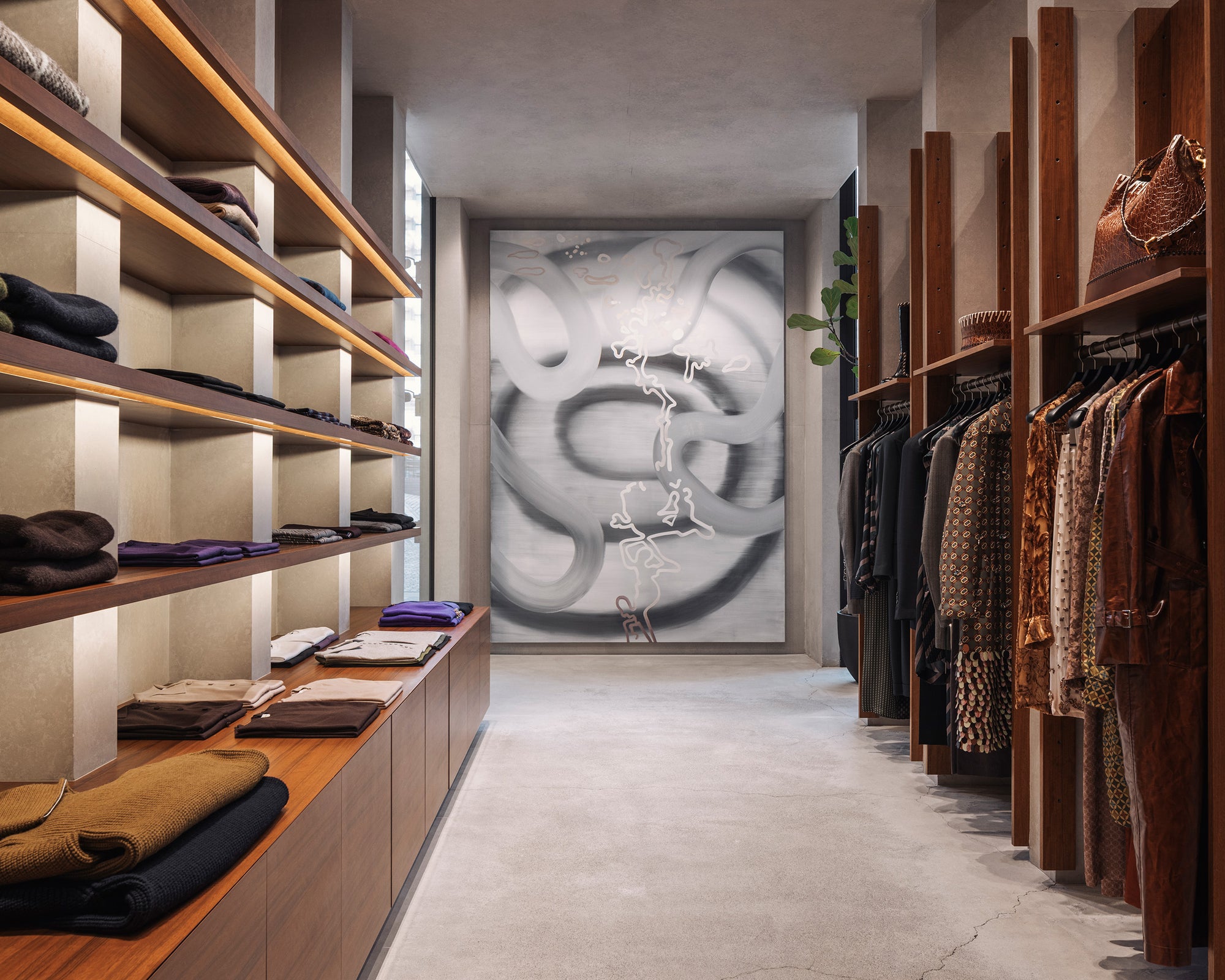 Modern walk-in closet with wooden shelves and clothing racks, featuring a large abstract painting on the wall.