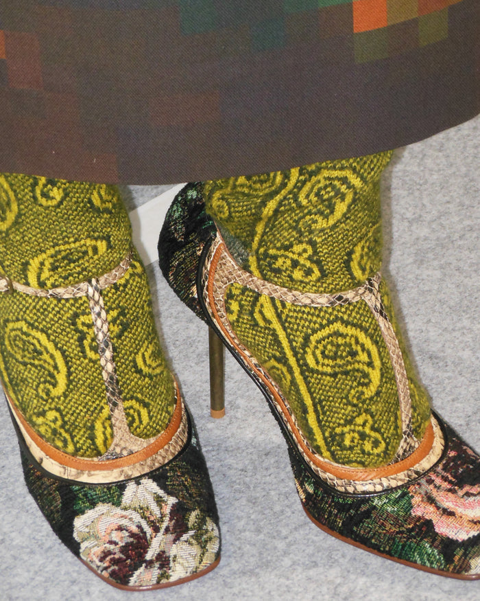 Pair of high-heeled shoes with intricate green and black patterned design on a gray background
