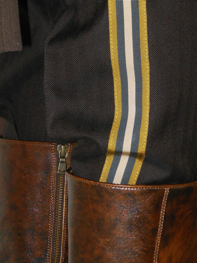 Close-up of a brown leather boot with a striped ribbon on a dark background
