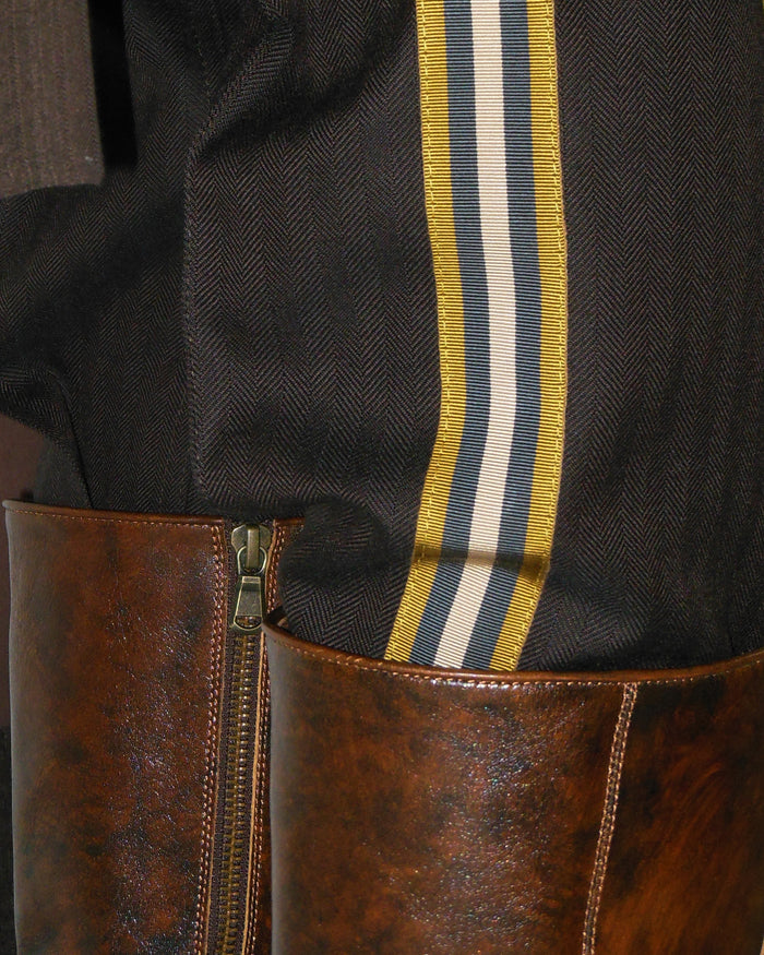 Close-up of a brown leather boot with a striped ribbon on a dark background